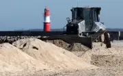 Sandhügel in Warnemünde: Planierraupe formt Strand für Küstenschutz und Tourismus